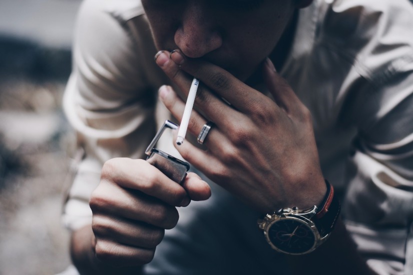 person lighting cigarette with zippo style lighter