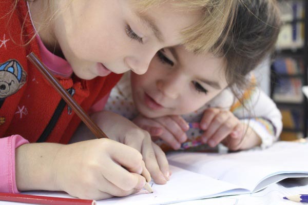 Two children writing with pencils