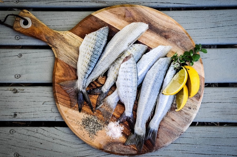 raw fish on a wooden board with lemon wedges