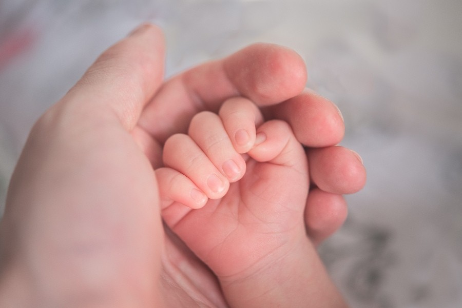 adult hand holding baby's hand