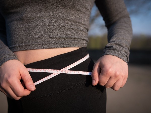 person holding measuring tape around waist 