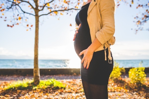 Pregnant person standing near autumn trees