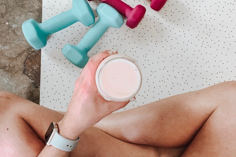 person sat cross legged holding protein shake