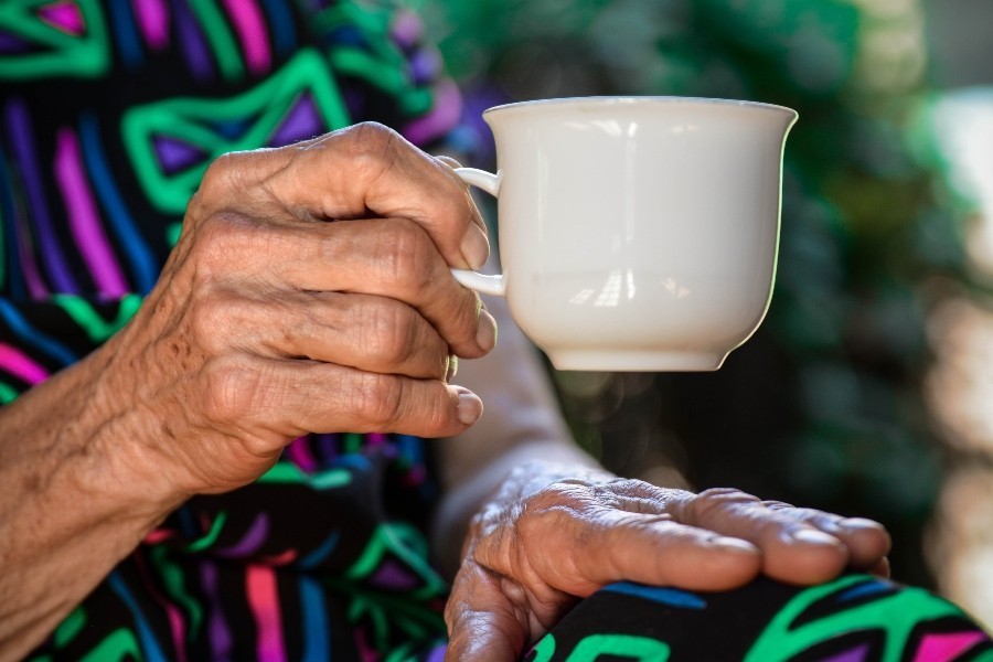 older person's hands holding cup